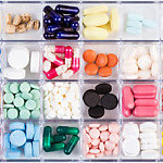 Various medicine pills and capsules in a plastic pill organizer.