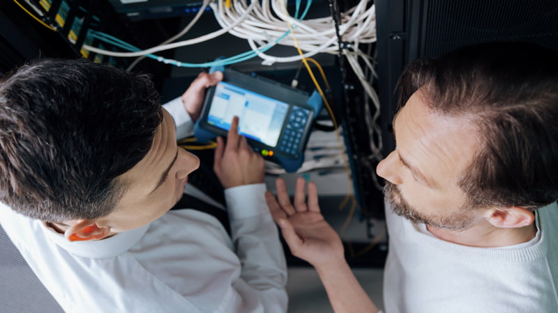 Two men, one holding a digital tablet, discuss work issues.