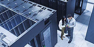 High-angle view of two technicians talking in a server room.