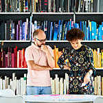 Close view of two colleagues absorbed in a discussion against a backdrop of colour-coordinated bookshelves.