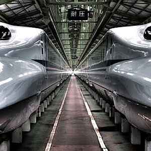 Two Japanese Shinkansen high-speed trains with vanishing view of station platform.