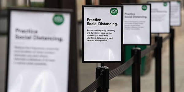 Signs explaining the need for social distancing while queueing are seen outside a Whole Foods health store in London, England. 