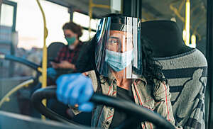 Female bus driver wears a protective transparent face shield during the COVID-19 pandemic.